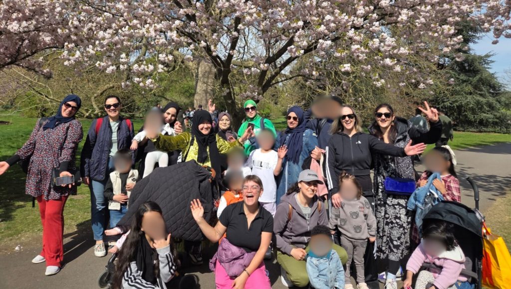Group of women and children under tree heavy with blossom